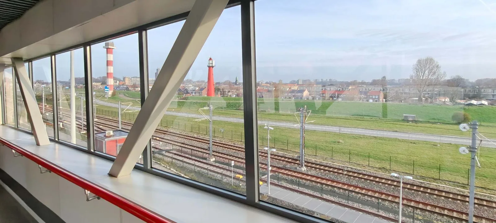 The glazed walkway at Hook of Holland ferry terminal, with the metro line below and the town's two lighthouses in the distance